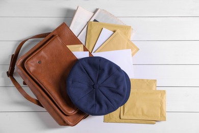 Brown postman's bag, envelopes, newspapers and hat on white wooden table, top view