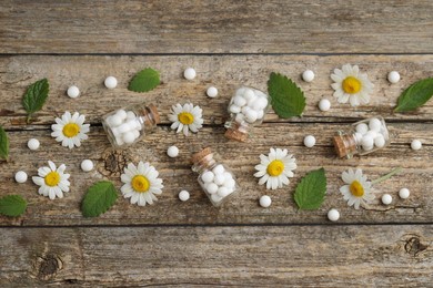 Homeopathic remedy. Flat lay composition with many pills, bottles and chamomile flowers on wooden table