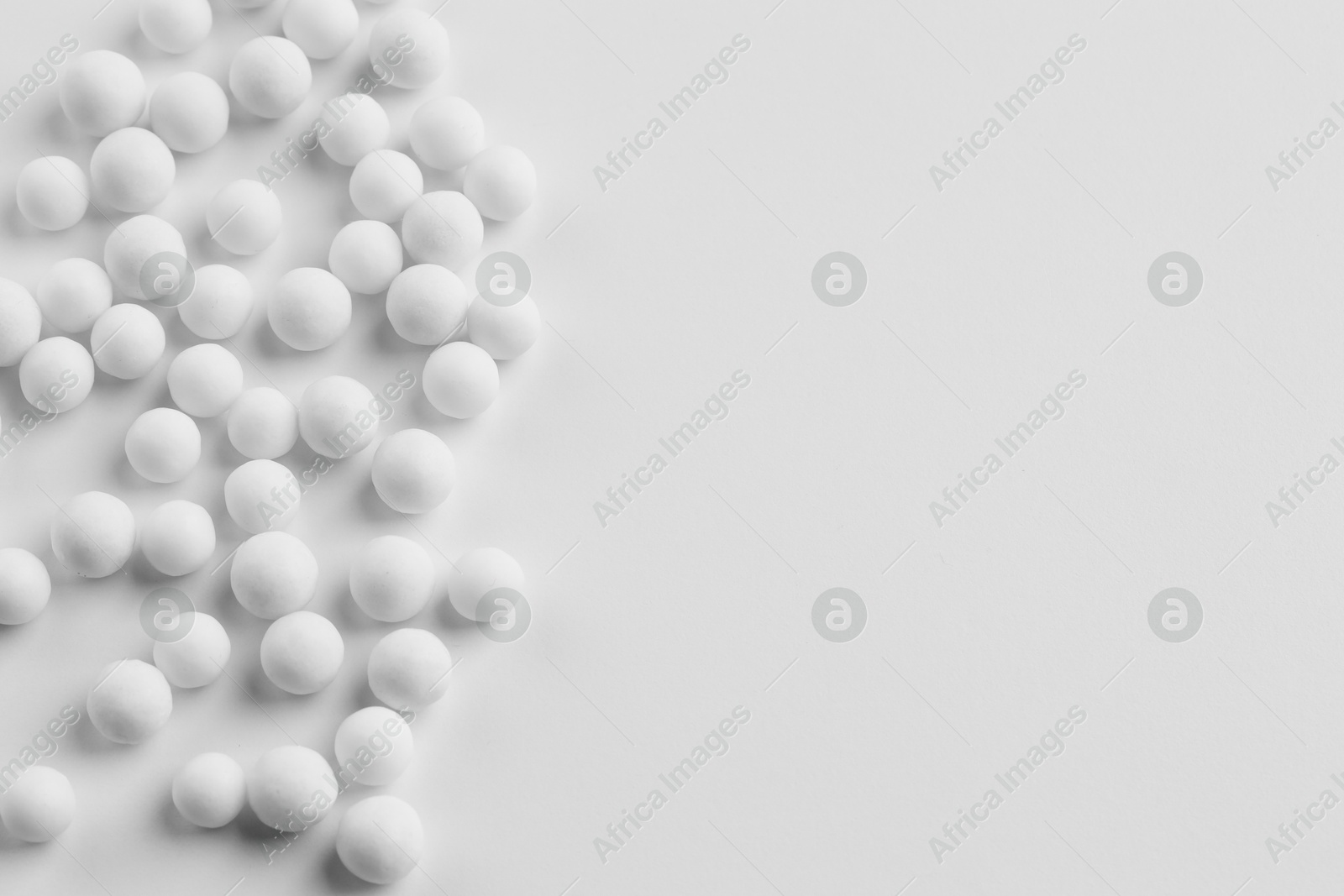 Photo of Homeopathic remedy. Many round pills on white background, top view. Space for text