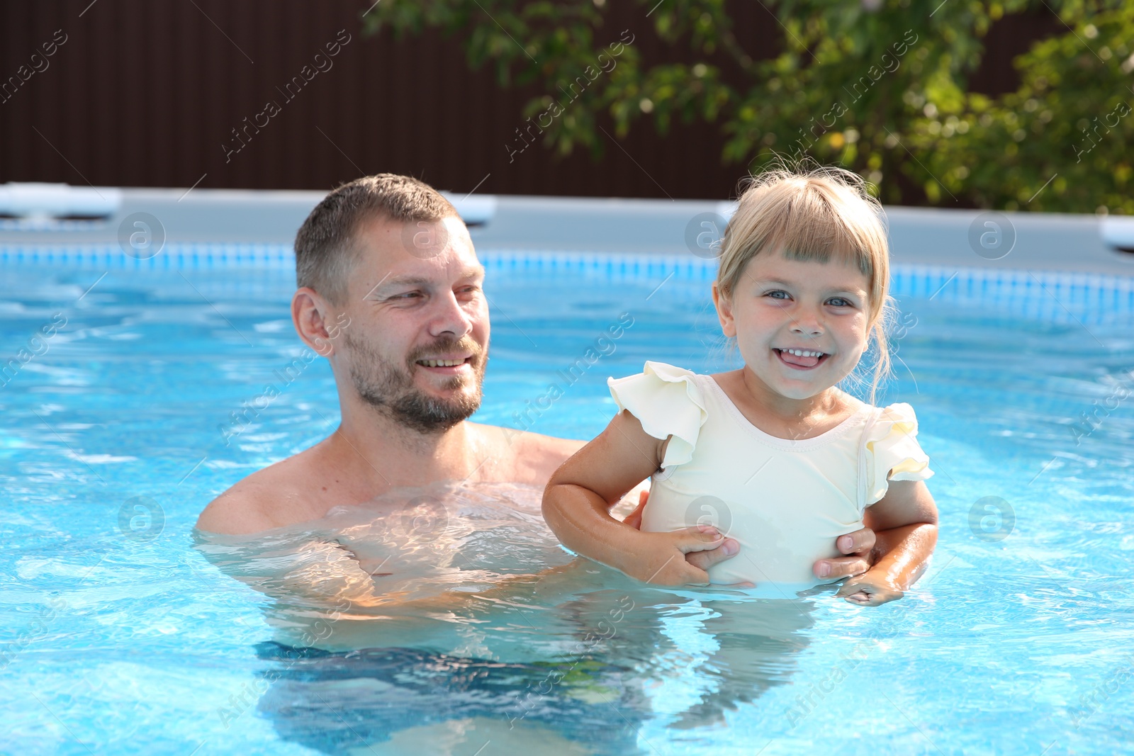 Photo of Happy father having fun with his daughter in swimming pool