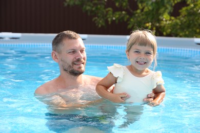 Photo of Happy father having fun with his daughter in swimming pool