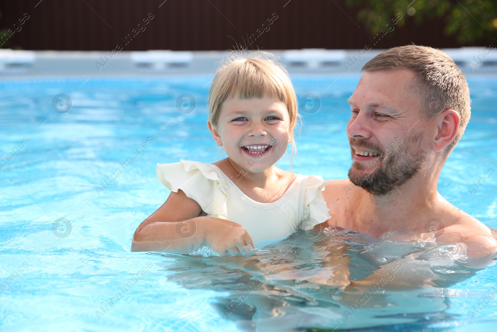 Photo of Happy father having fun with his daughter in swimming pool