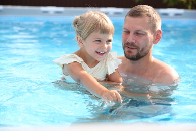 Photo of Happy father having fun with his daughter in swimming pool