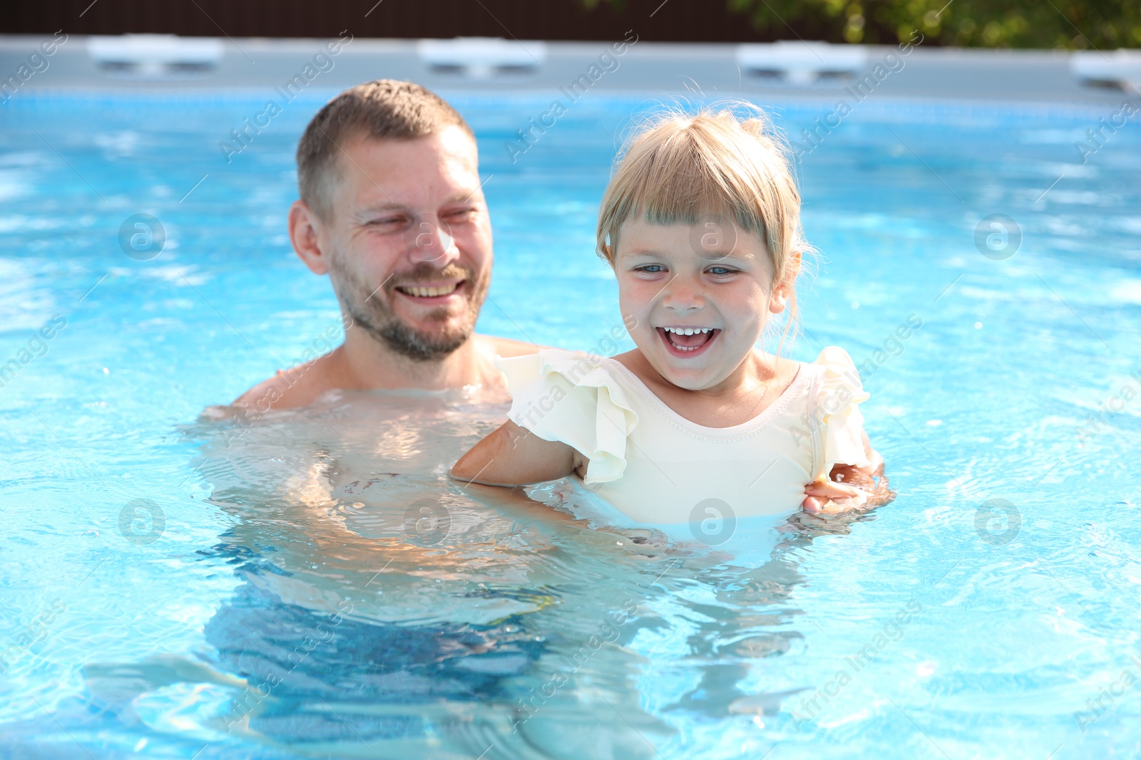 Photo of Happy father having fun with his daughter in swimming pool