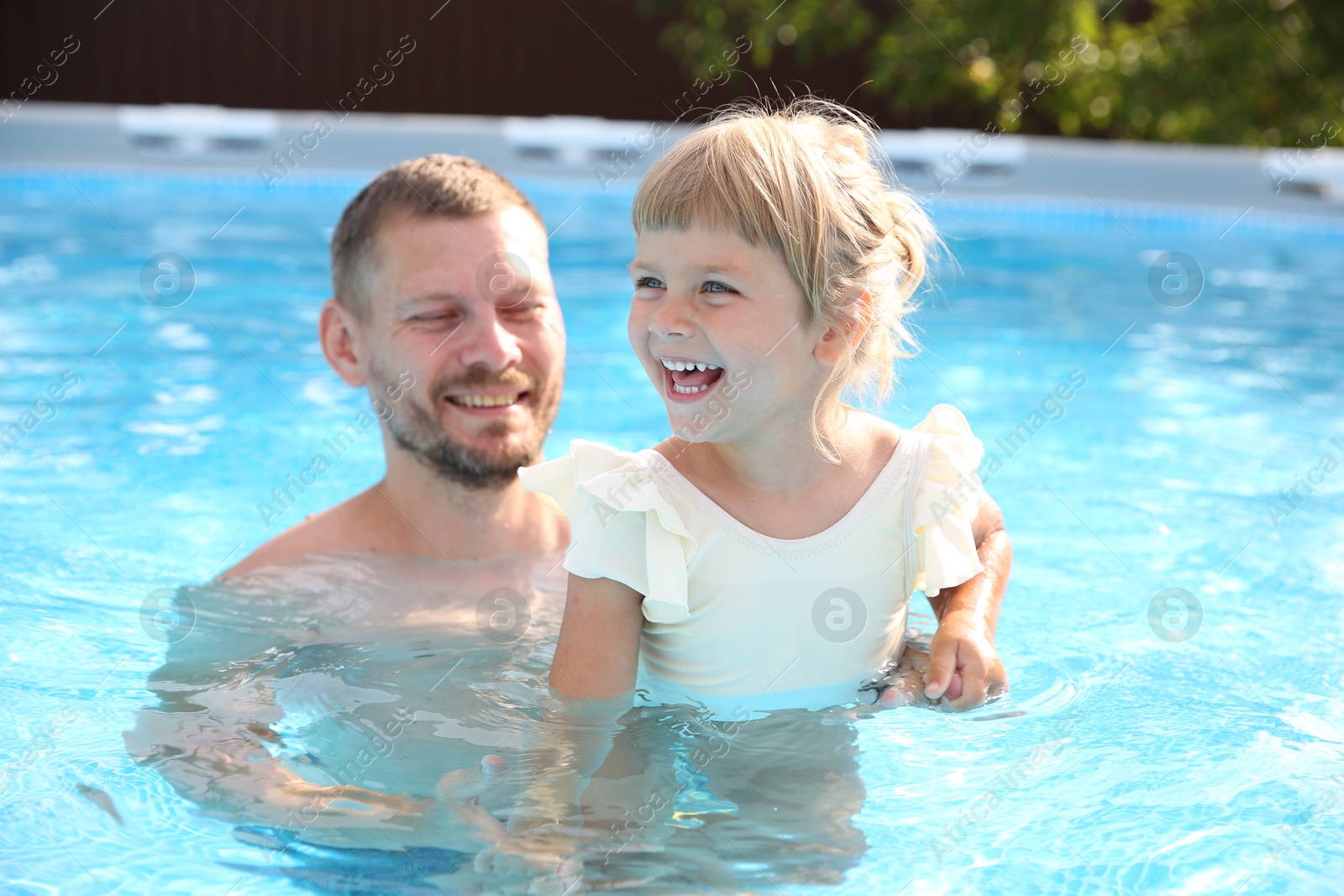 Photo of Happy father having fun with his daughter in swimming pool