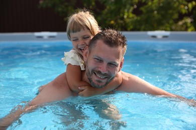 Photo of Happy father having fun with his daughter in swimming pool