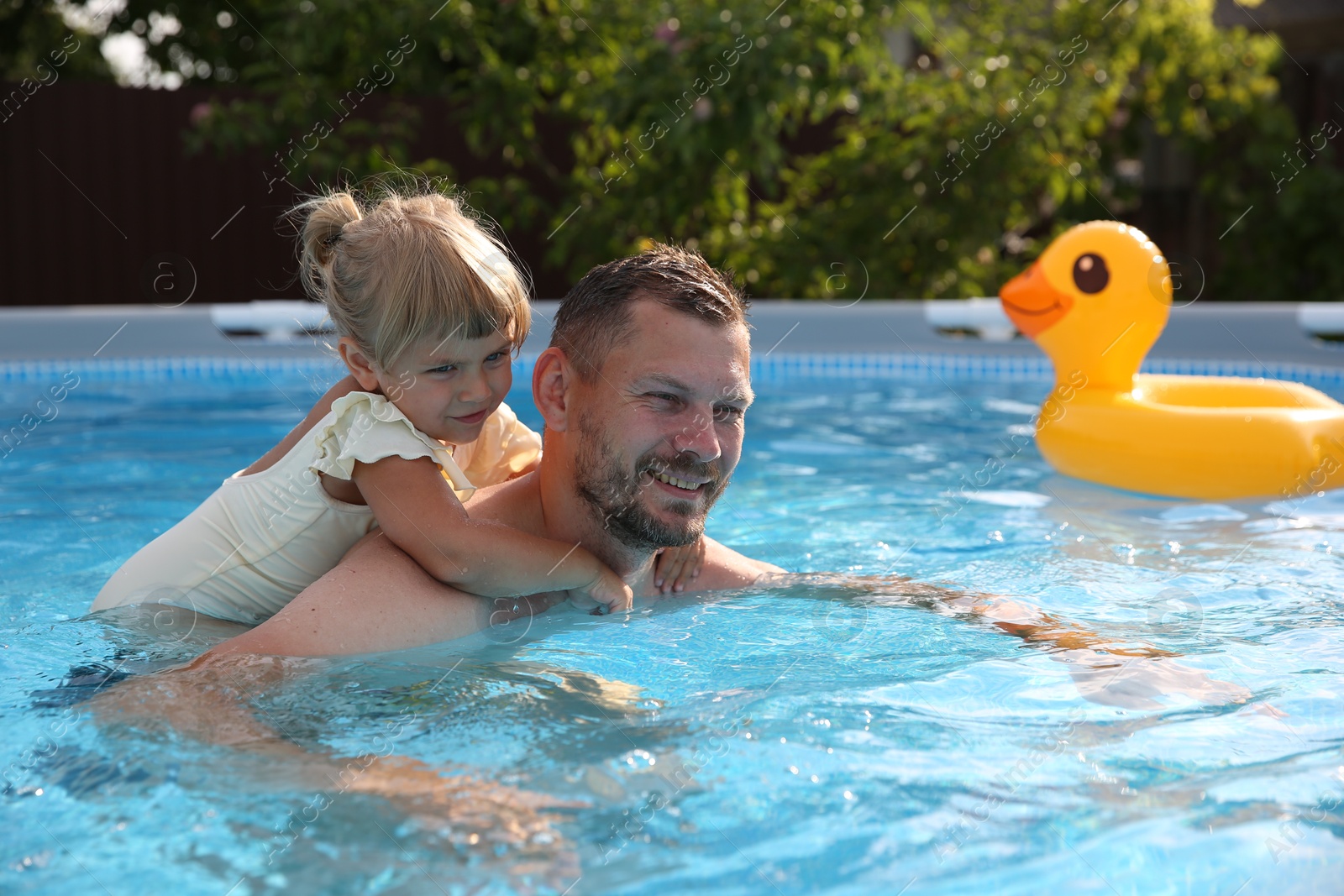 Photo of Happy father having fun with his daughter in swimming pool