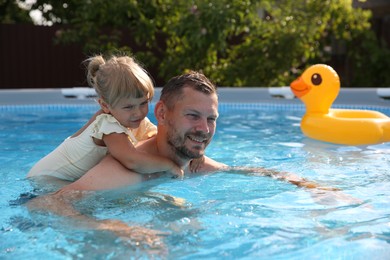 Photo of Happy father having fun with his daughter in swimming pool