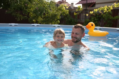 Photo of Happy father having fun with his daughter in swimming pool, space for text