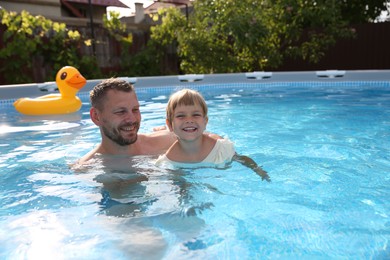 Happy father having fun with his daughter in swimming pool, space for text