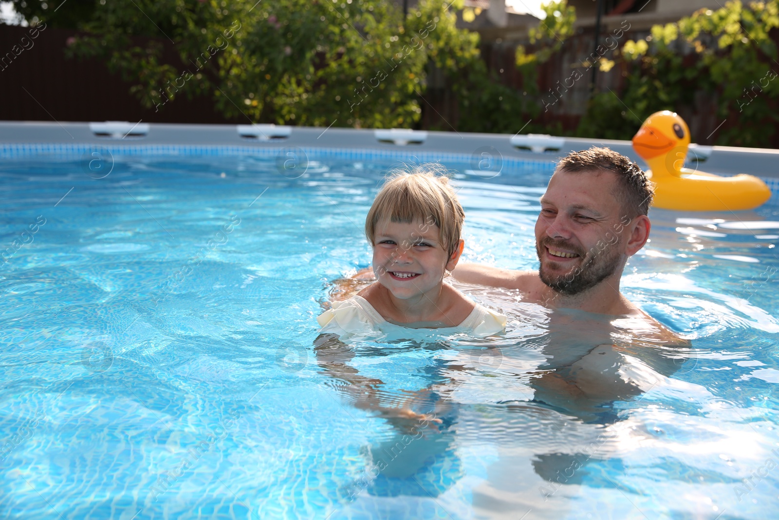 Photo of Happy father having fun with his daughter in swimming pool, space for text