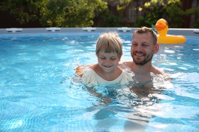 Photo of Happy father having fun with his daughter in swimming pool, space for text