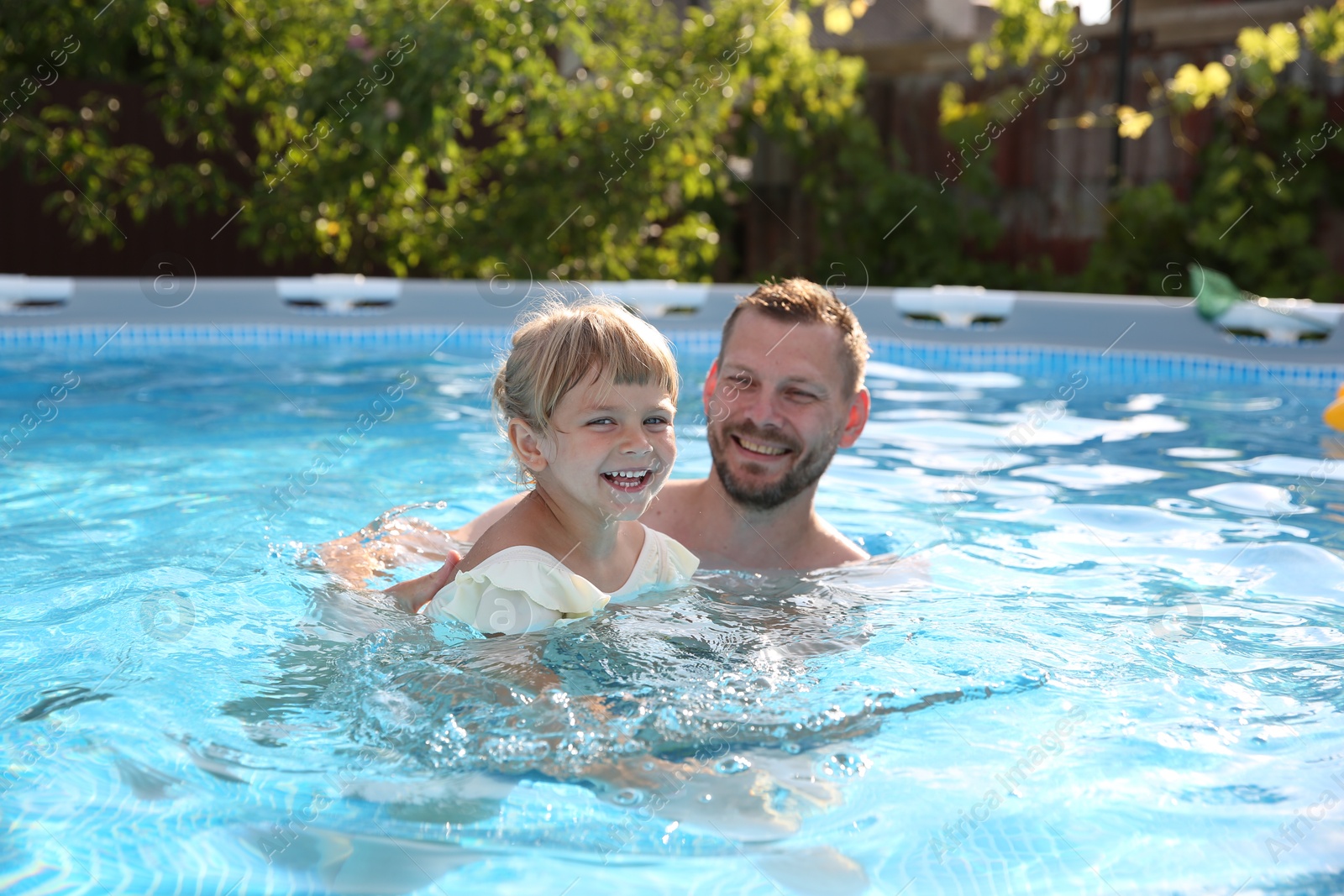 Photo of Happy father having fun with his daughter in swimming pool