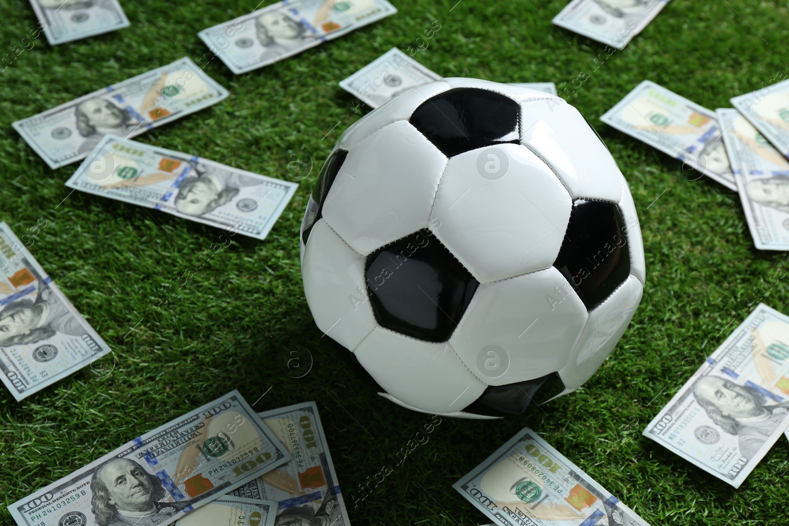 Photo of Soccer ball and dollar banknotes on green grass outdoors