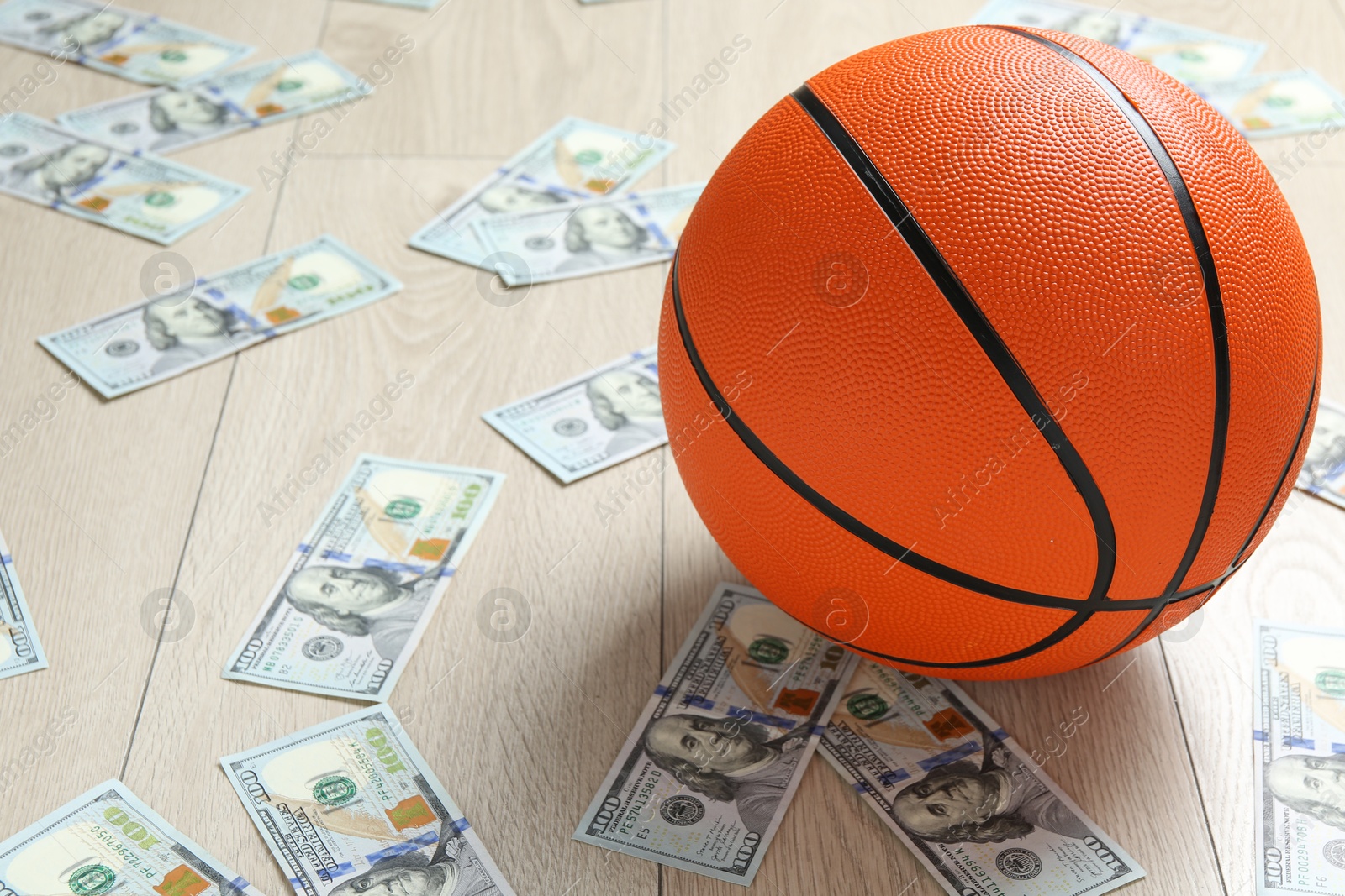 Photo of Basketball ball and dollar banknotes on wooden table