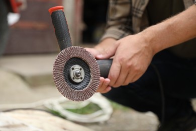 Photo of Man with angle grinder outdoors, closeup view