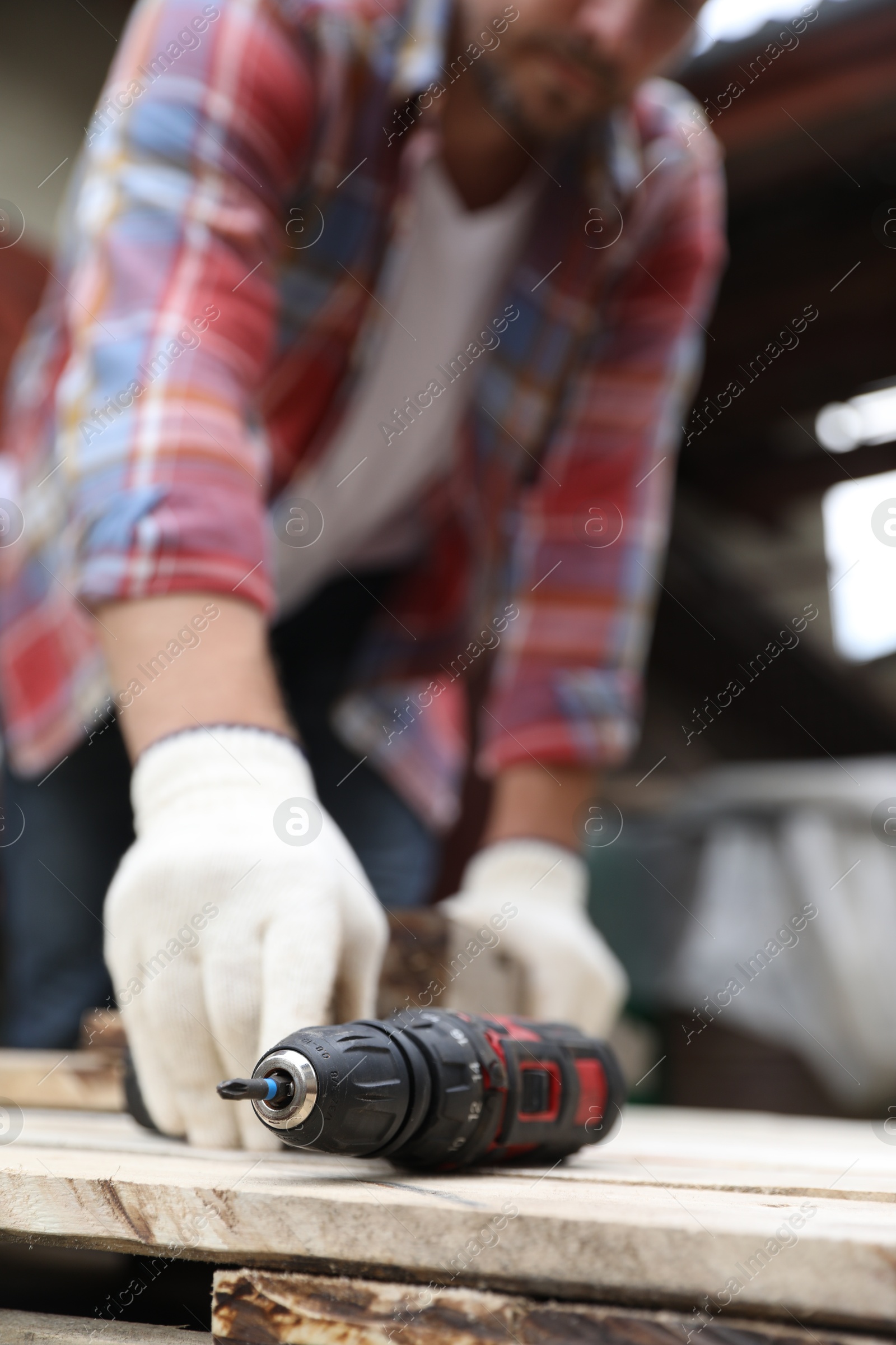 Photo of Man working with electric screwdriver outdoors, closeup