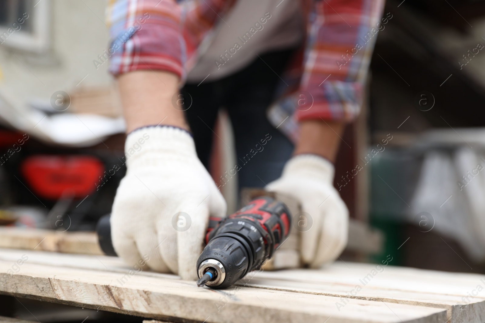 Photo of Man working with electric screwdriver outdoors, closeup