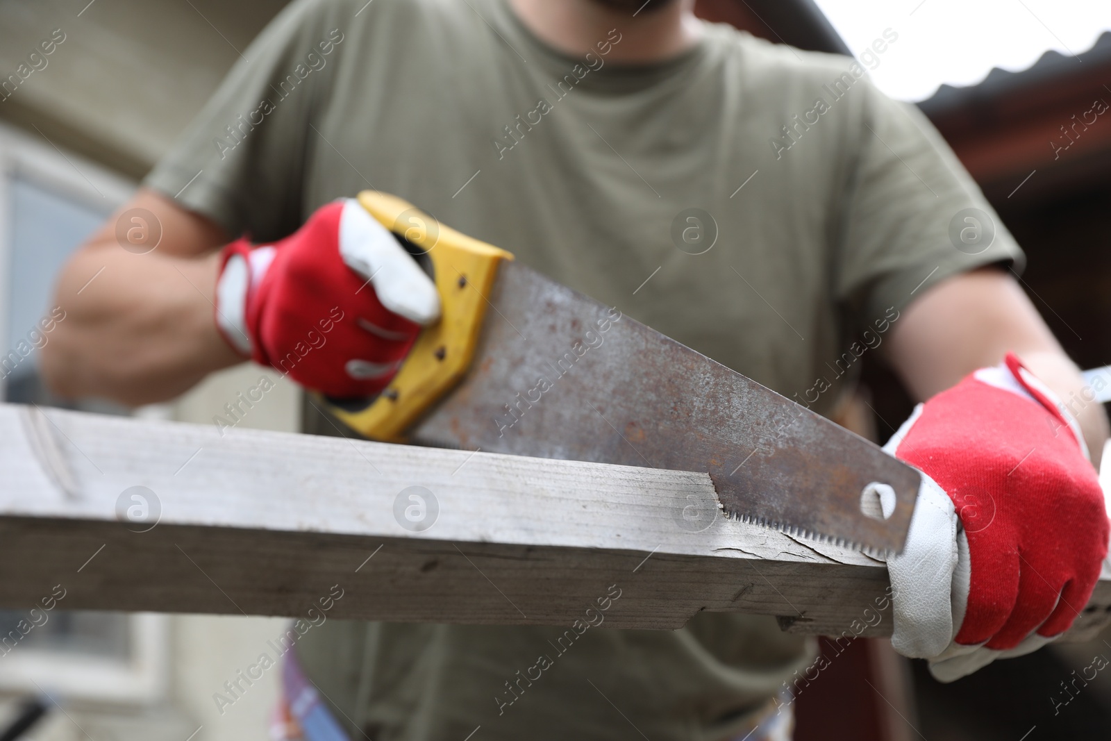 Photo of Man sawing wooden plank in backyard, closeup