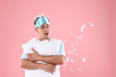 Photo of Overslept man with sleep mask and pillow on pink background