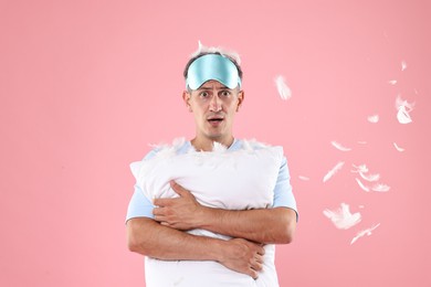 Photo of Overslept man with sleep mask and pillow on pink background