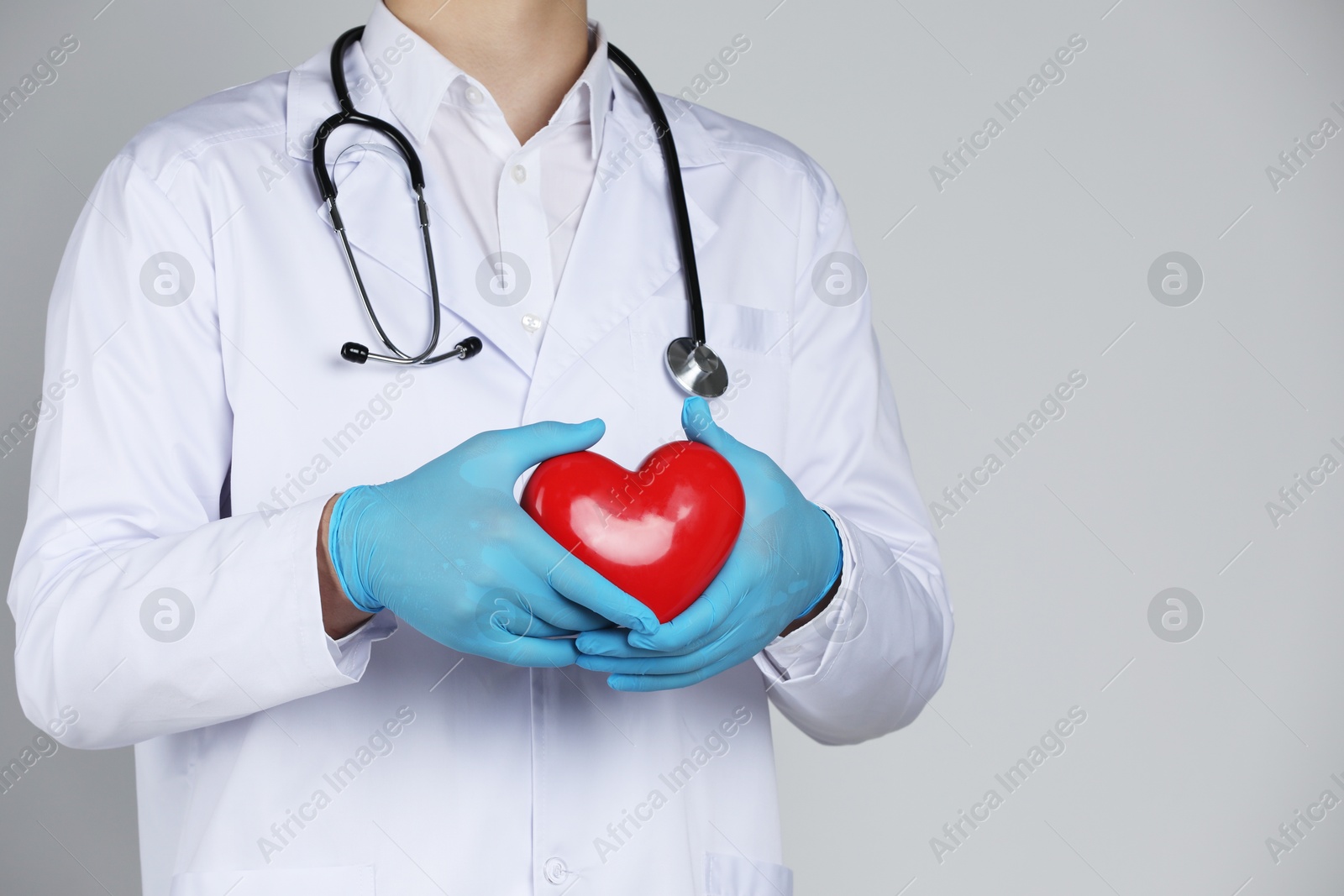 Photo of Doctor with red heart on grey background, closeup