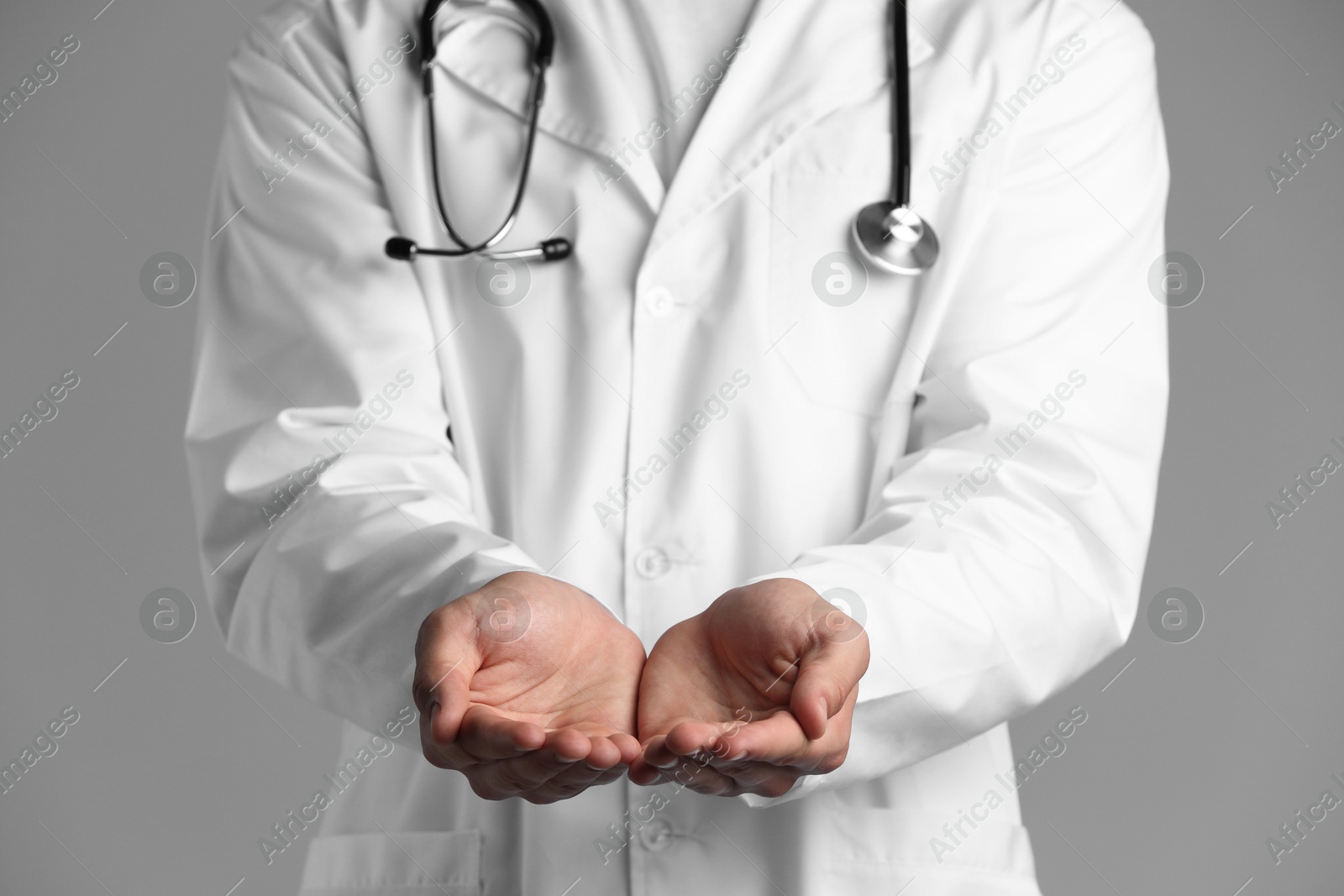 Photo of Doctor holding something on grey background, closeup