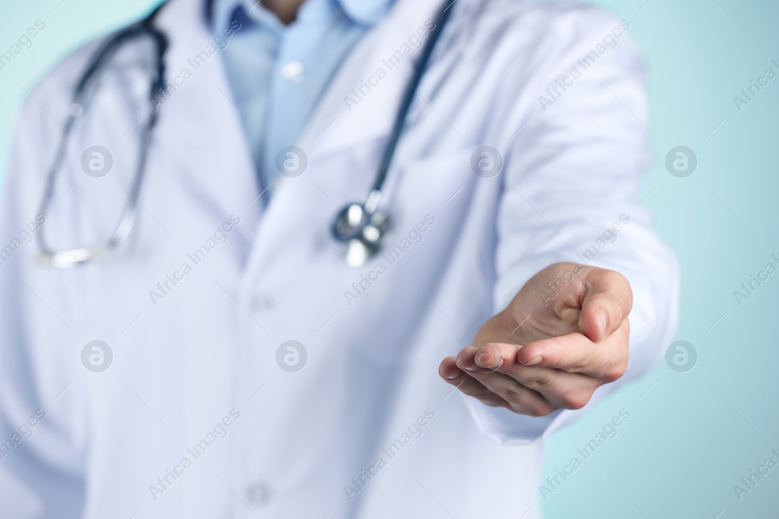 Photo of Doctor holding something on light blue background, closeup