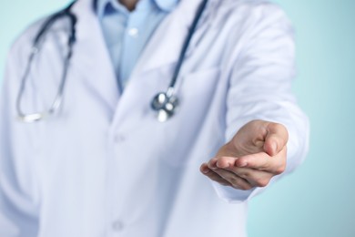 Doctor holding something on light blue background, closeup