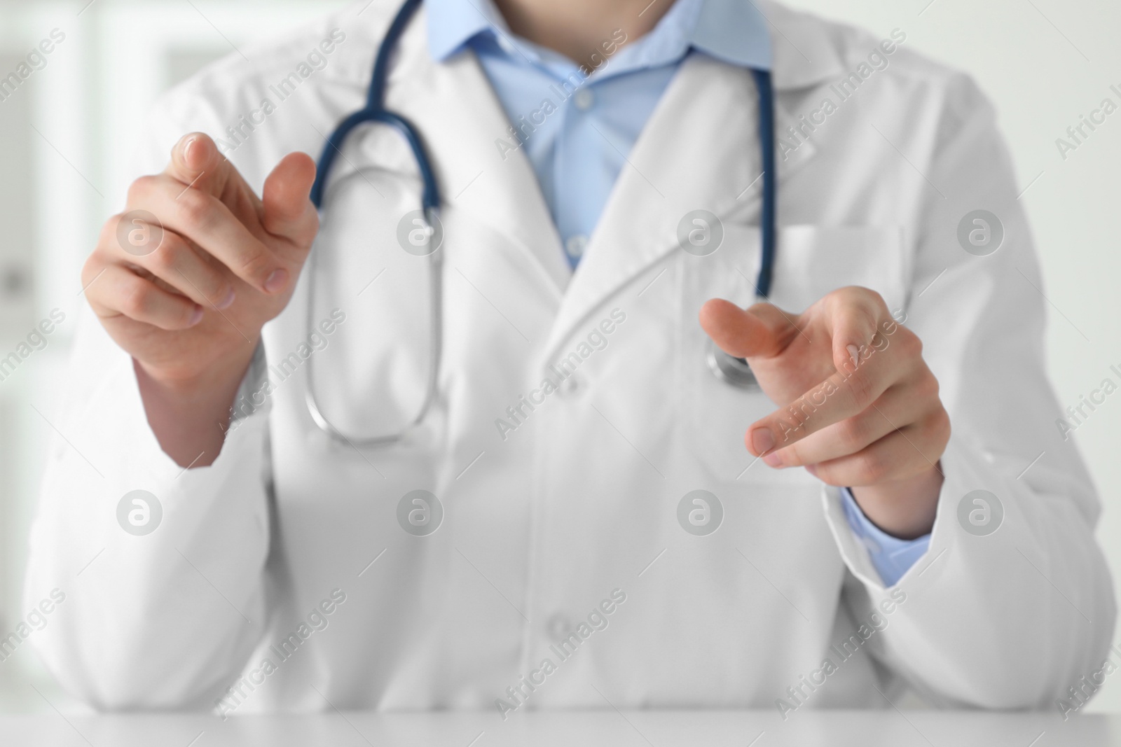 Photo of Doctor pointing at something at white table in clinic, closeup