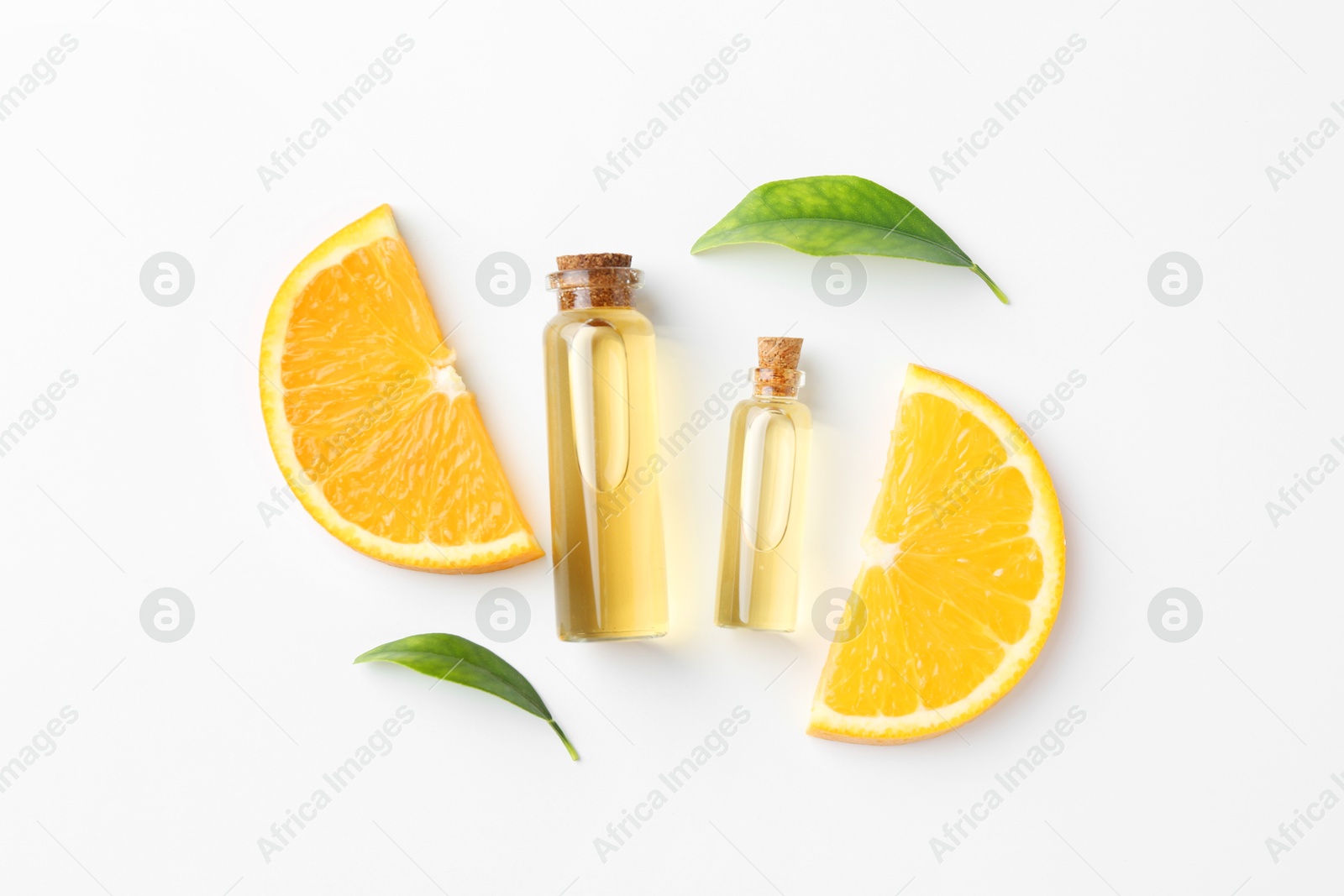 Photo of Bottles of essential oils, orange and green leaves on white background, flat lay