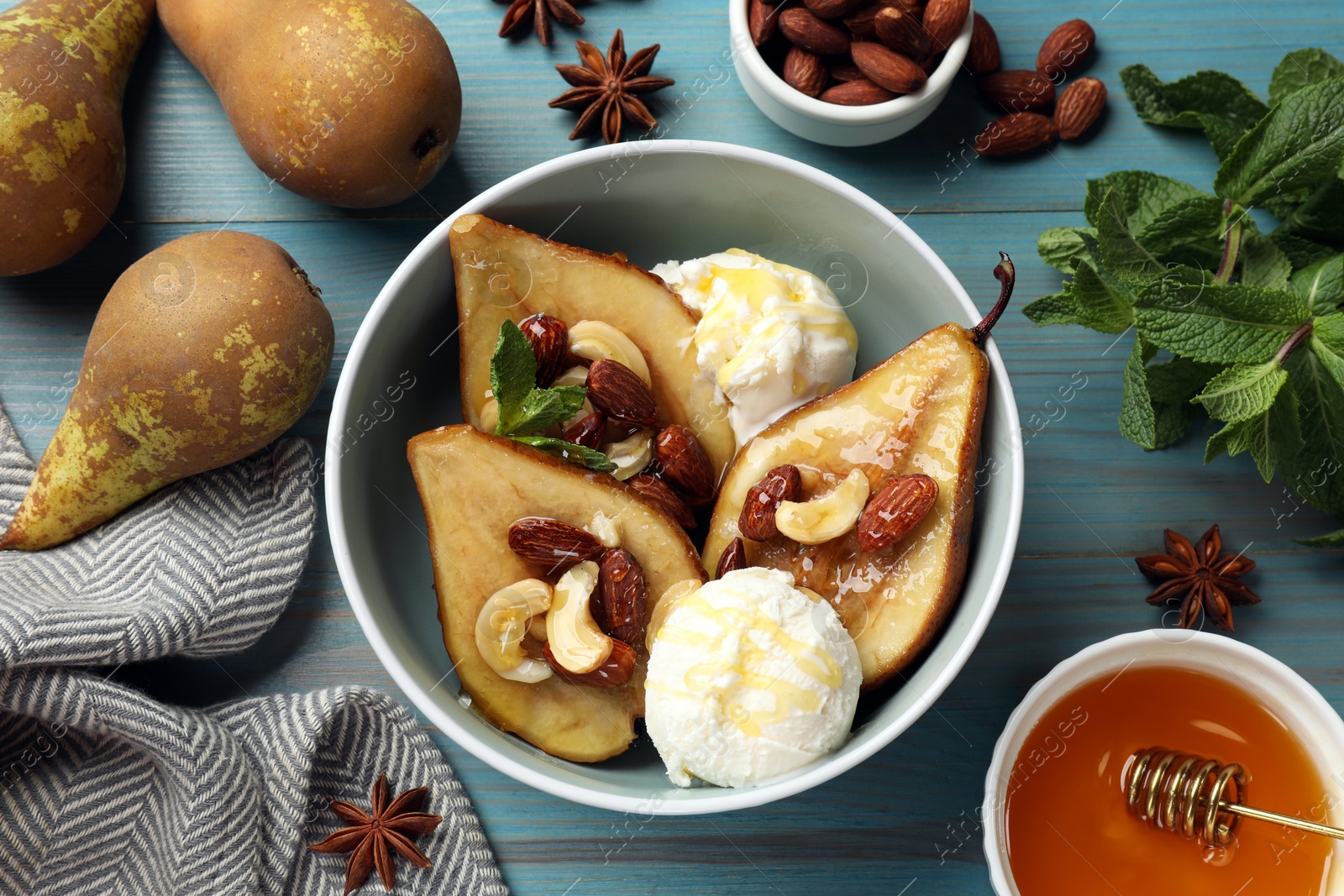 Photo of Delicious baked pears with nuts, ice cream and honey in bowl on light blue wooden table, flat lay