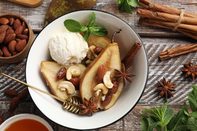 Photo of Delicious baked pears with nuts, ice cream, anise stars and honey in bowl on wooden rustic table, flat lay