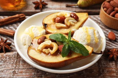 Delicious baked pears with nuts, ice cream, mint and honey on wooden rustic table, closeup