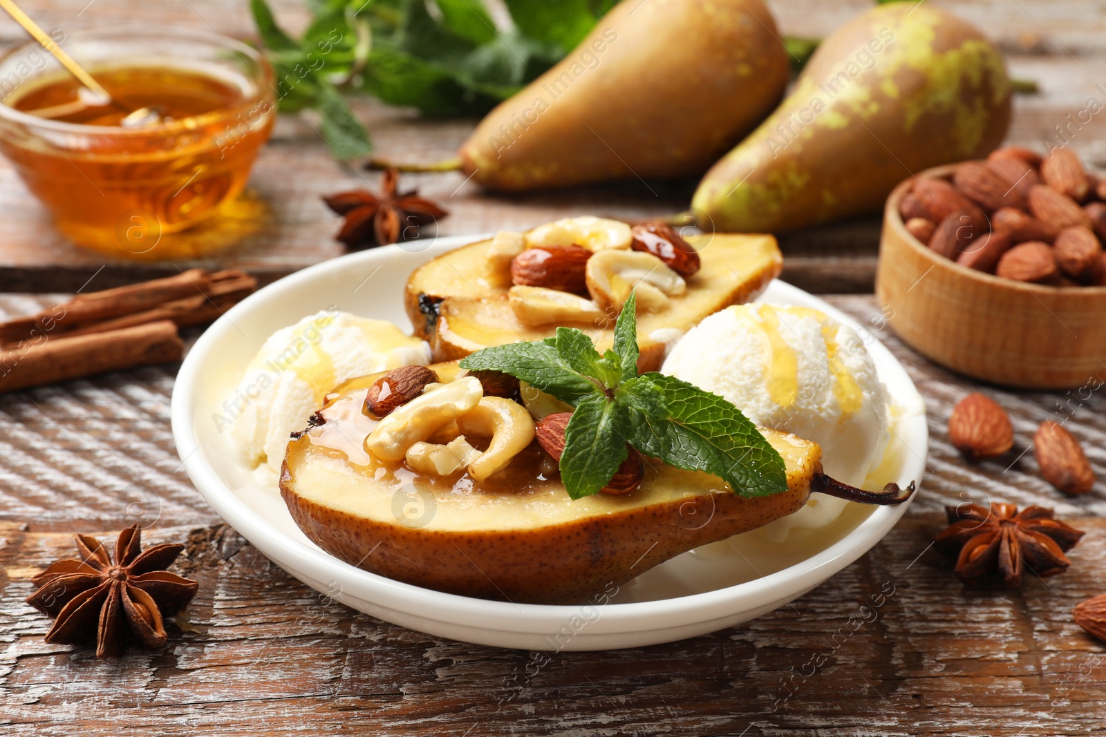 Photo of Delicious baked pears with nuts, ice cream, mint and honey on wooden rustic table, closeup