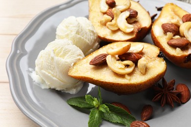 Delicious baked pears with nuts, ice cream, mint and honey on light wooden table, closeup