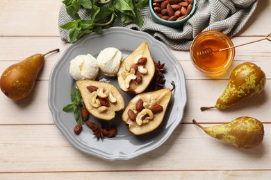 Delicious baked pears with nuts, ice cream, anise stars, mint and honey on light wooden table, flat lay