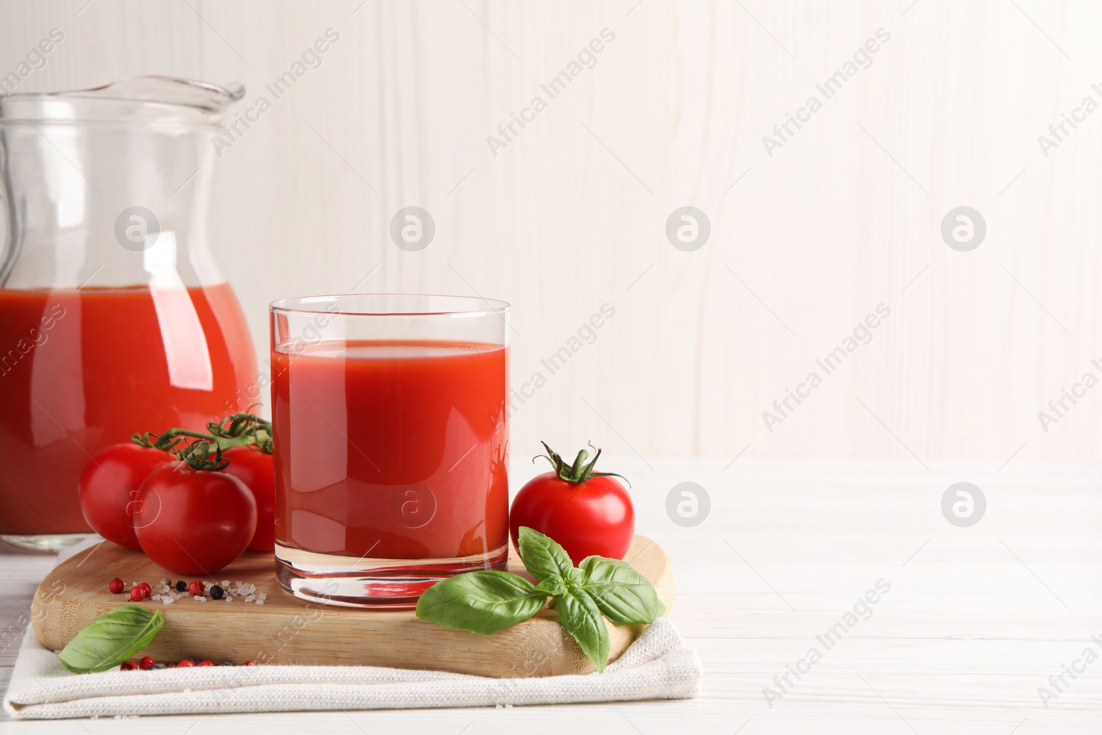 Photo of Tasty tomato juice with fresh vegetables and spices on white wooden table, space for text