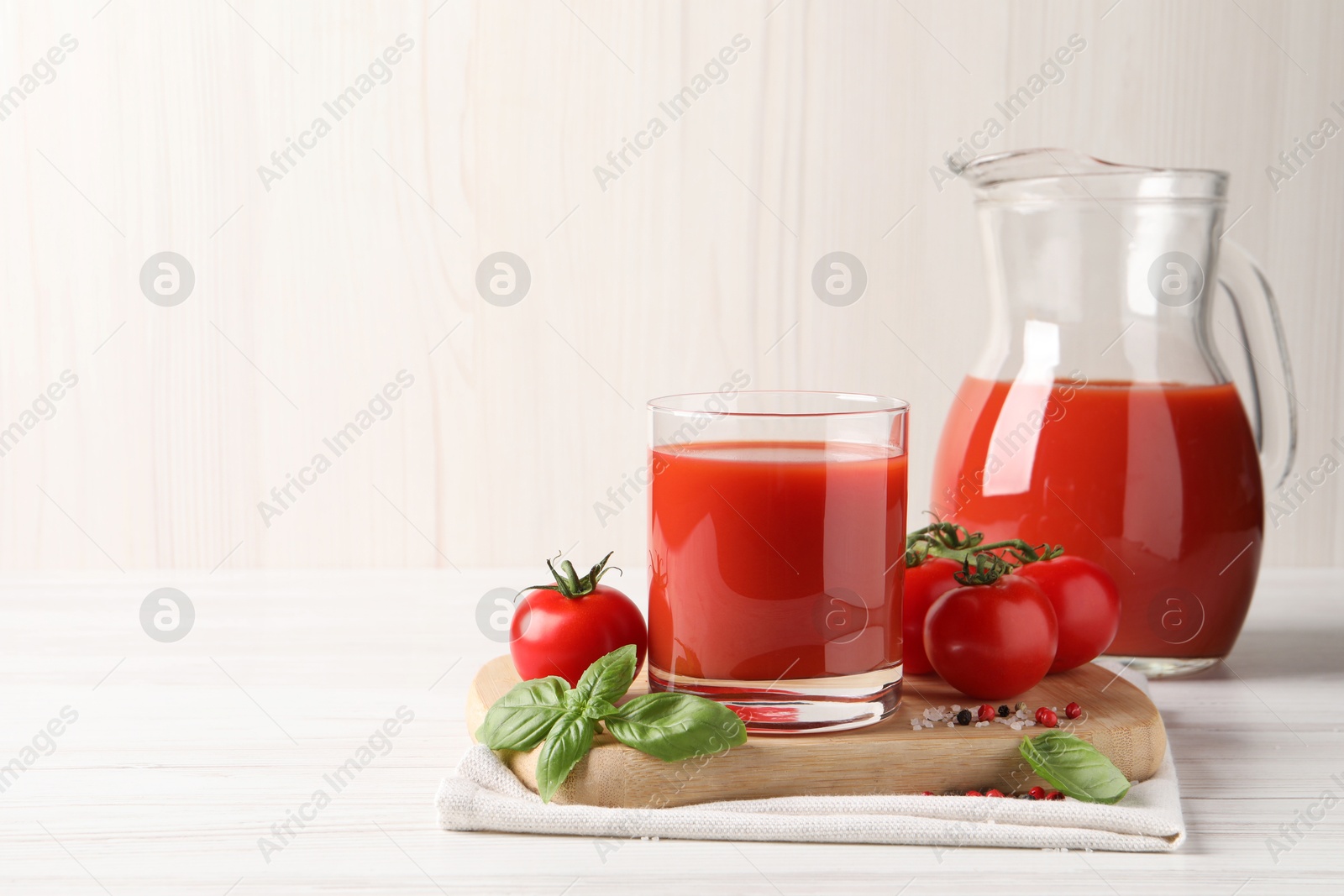 Photo of Tasty tomato juice with fresh vegetables and spices on white wooden table, space for text