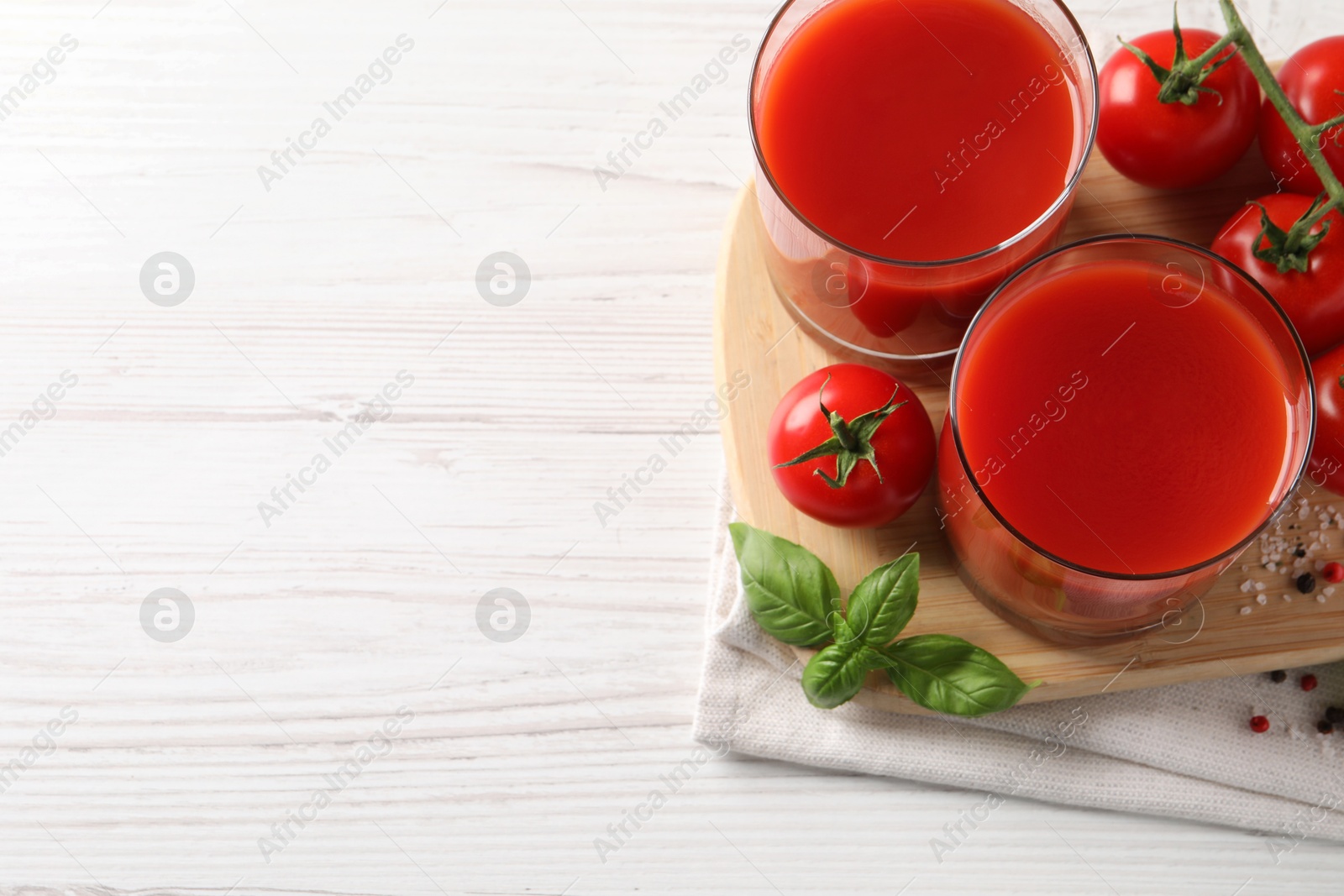 Photo of Tasty tomato juice in glasses with fresh vegetables and spices on white wooden table, flat lay. Space for text