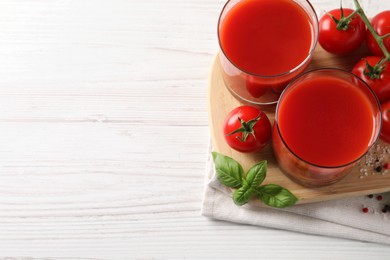 Tasty tomato juice in glasses with fresh vegetables and spices on white wooden table, flat lay. Space for text