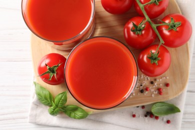 Tasty tomato juice in glasses with fresh vegetables and spices on white wooden table, flat lay