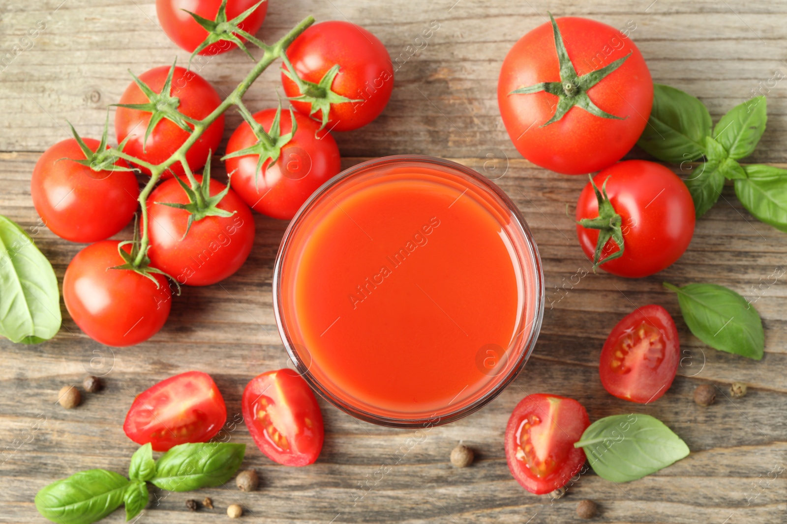 Photo of Tasty tomato juice in glass with fresh vegetables and spices on wooden table, flat lay