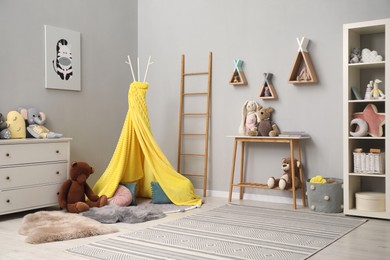 Photo of Stylish child room interior with modern furniture, toys and play tent