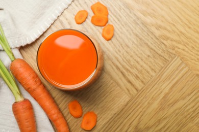 Photo of Healthy juice in glass and fresh carrot on wooden table, flat lay. Space for text