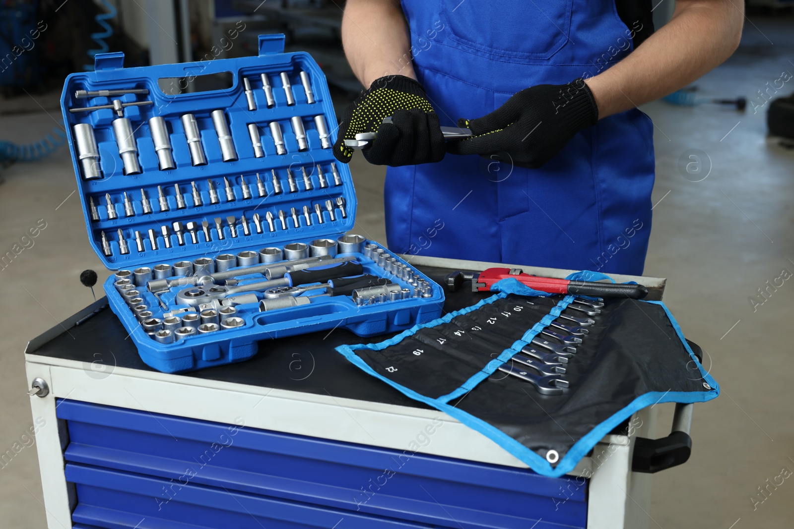 Photo of Auto mechanic with different tools at automobile repair shop, closeup