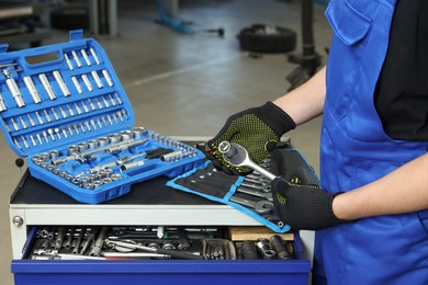 Auto mechanic with different tools at automobile repair shop, closeup