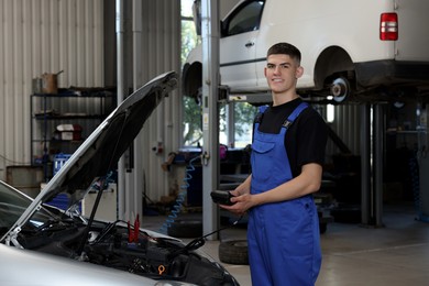 Young auto mechanic doing car diagnostic at automobile repair shop