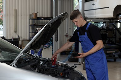 Photo of Young auto mechanic doing car diagnostic at automobile repair shop