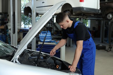 Photo of Young auto mechanic fixing car at automobile repair shop